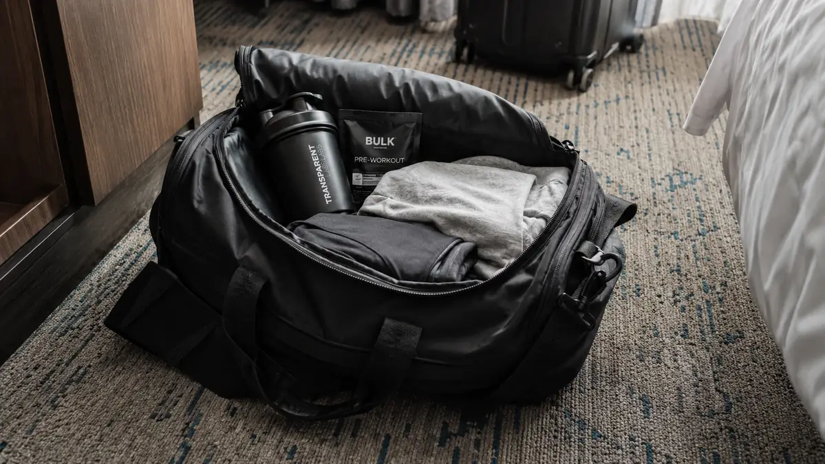 A packed gym bag with a shaker bottle and single-serve powder packet for a weekend trip