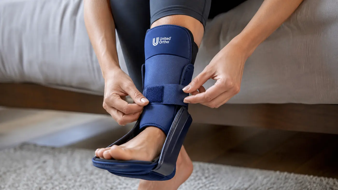 Hands adjusting the straps of a night splint being fitted onto a left foot before bed