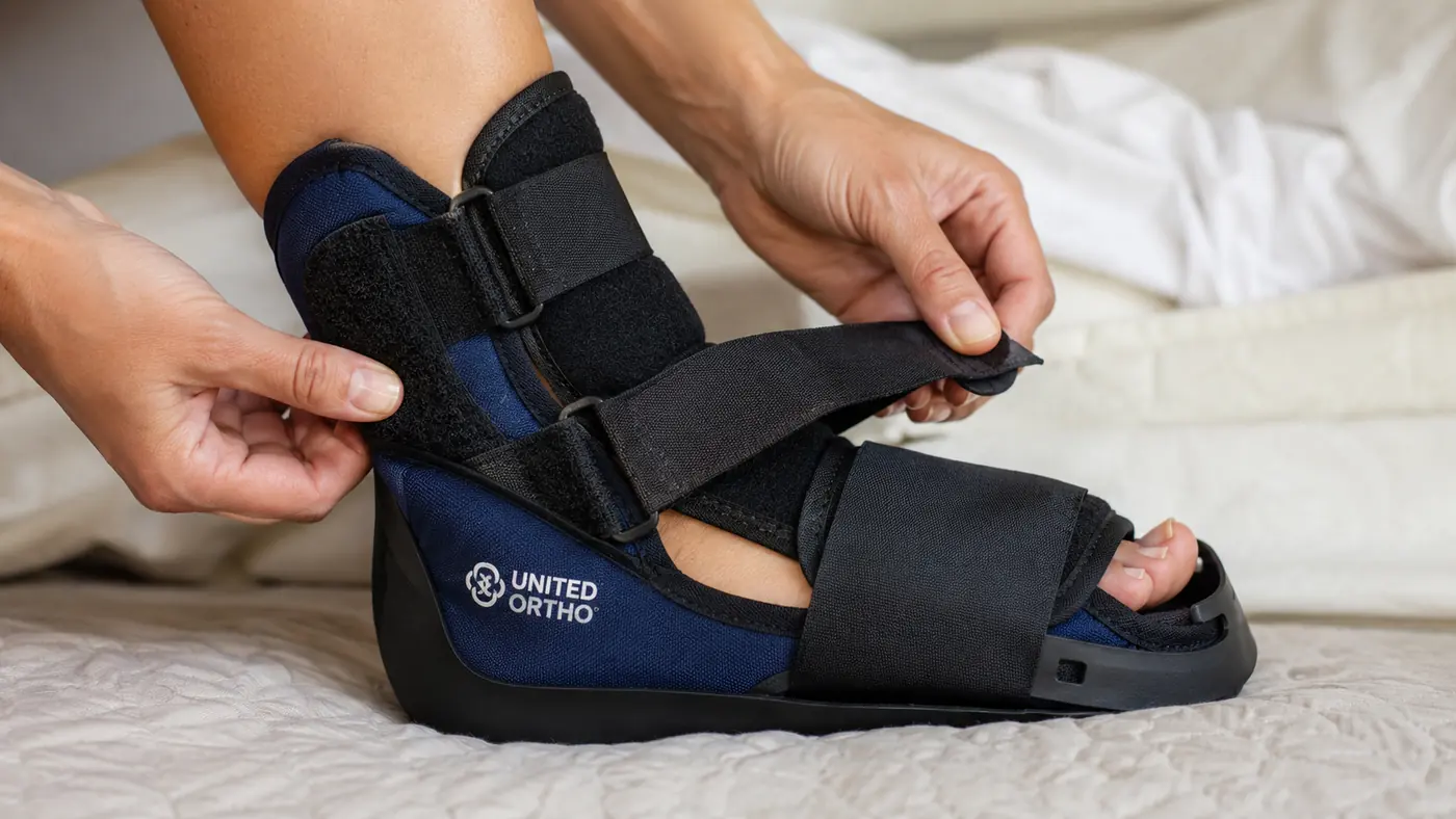Hands adjusting the straps of a night splint around a foot and lower leg to check for even, comfortable tightness