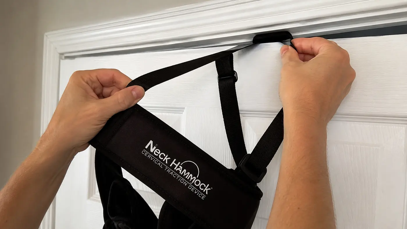 Hands adjusting the neck hammock strap over a door hinge before a session