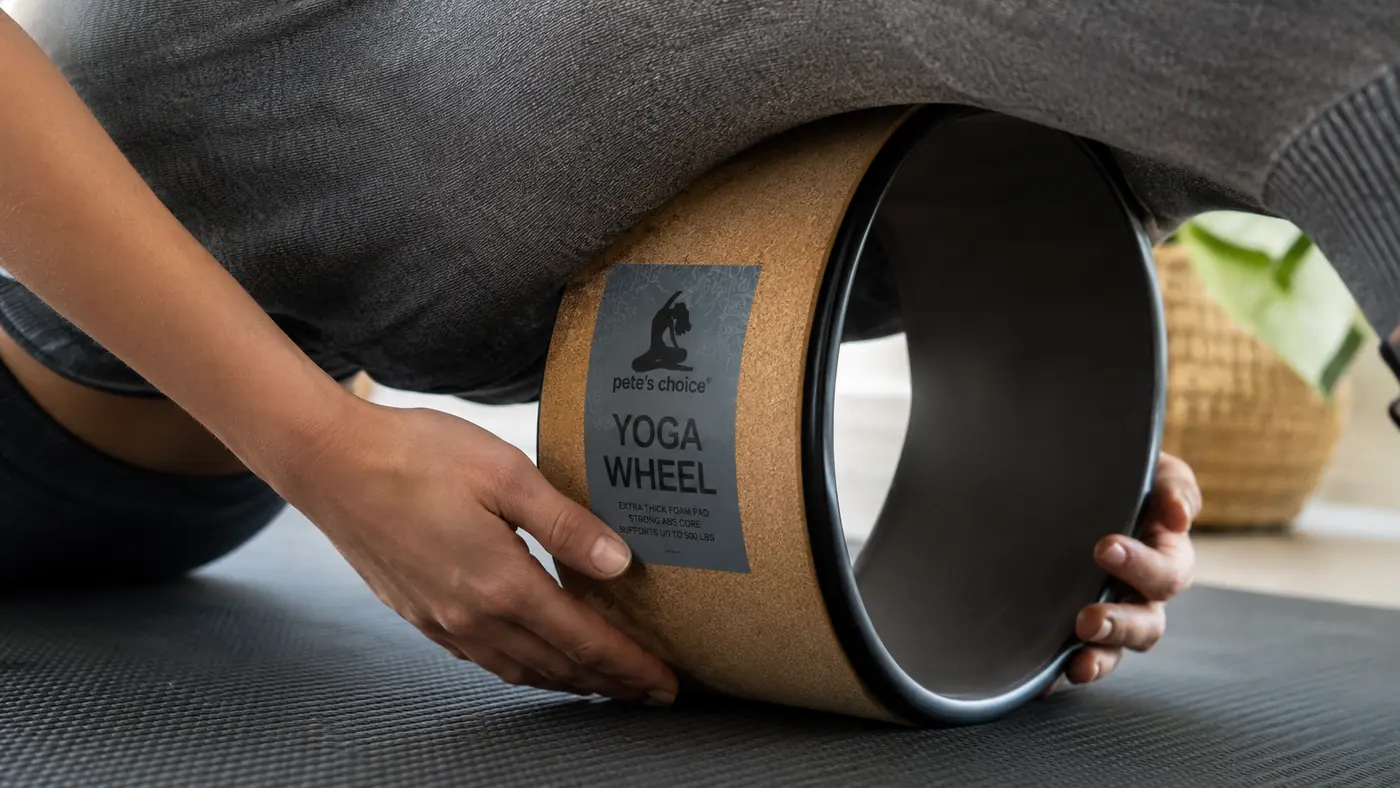 Hands positioning a yoga wheel under the mid-back for a passive thoracic extension hold